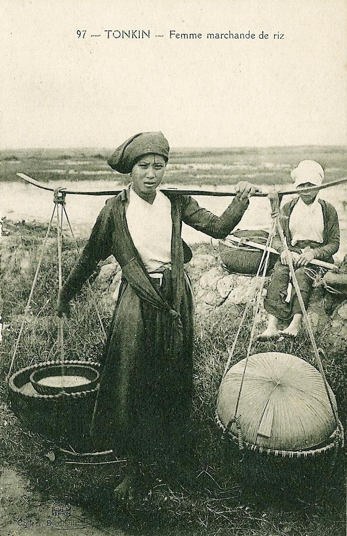 Phụ nữ gánh gạo trên đường đến chợ.